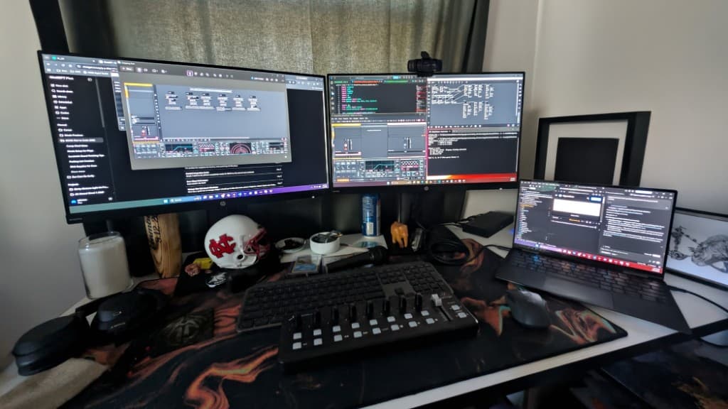 Audio-visual programming workspace with monitors, MIDI controller, and lighting software