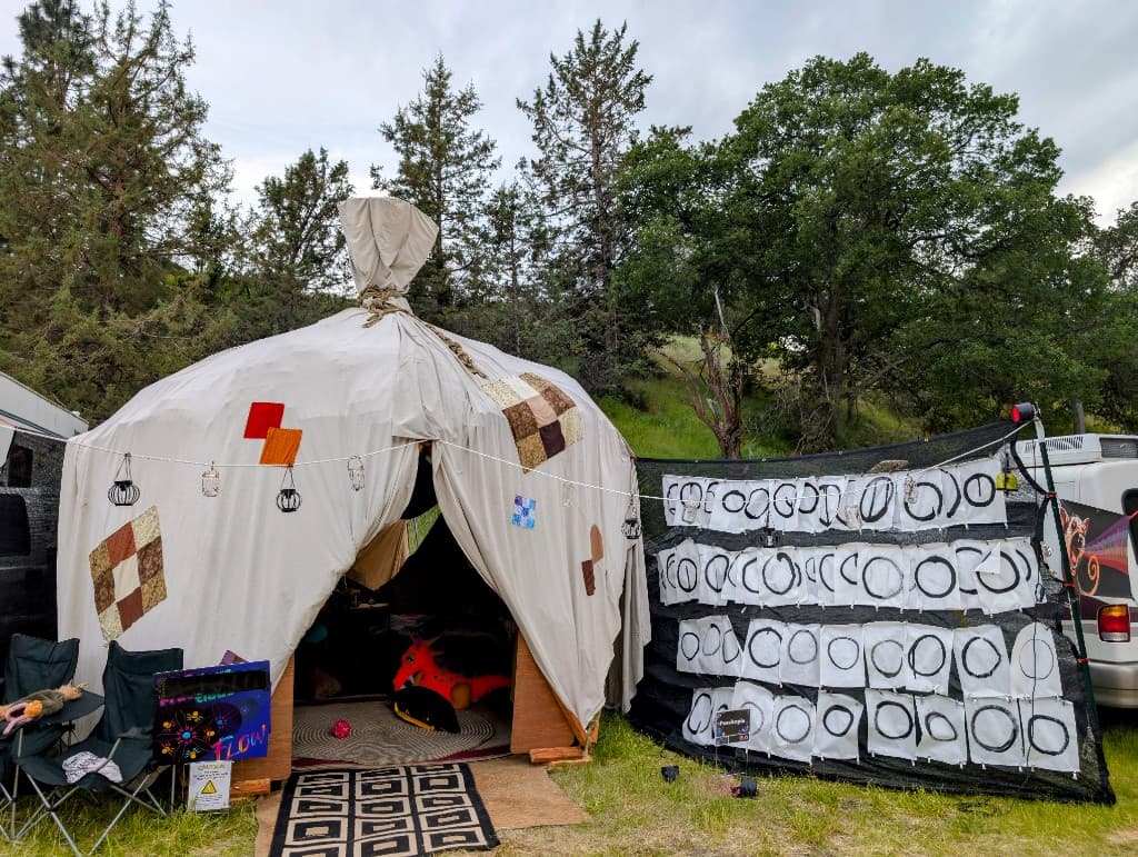 Outdoor enso painting ritual setup with cushions, brushes, and painted circles